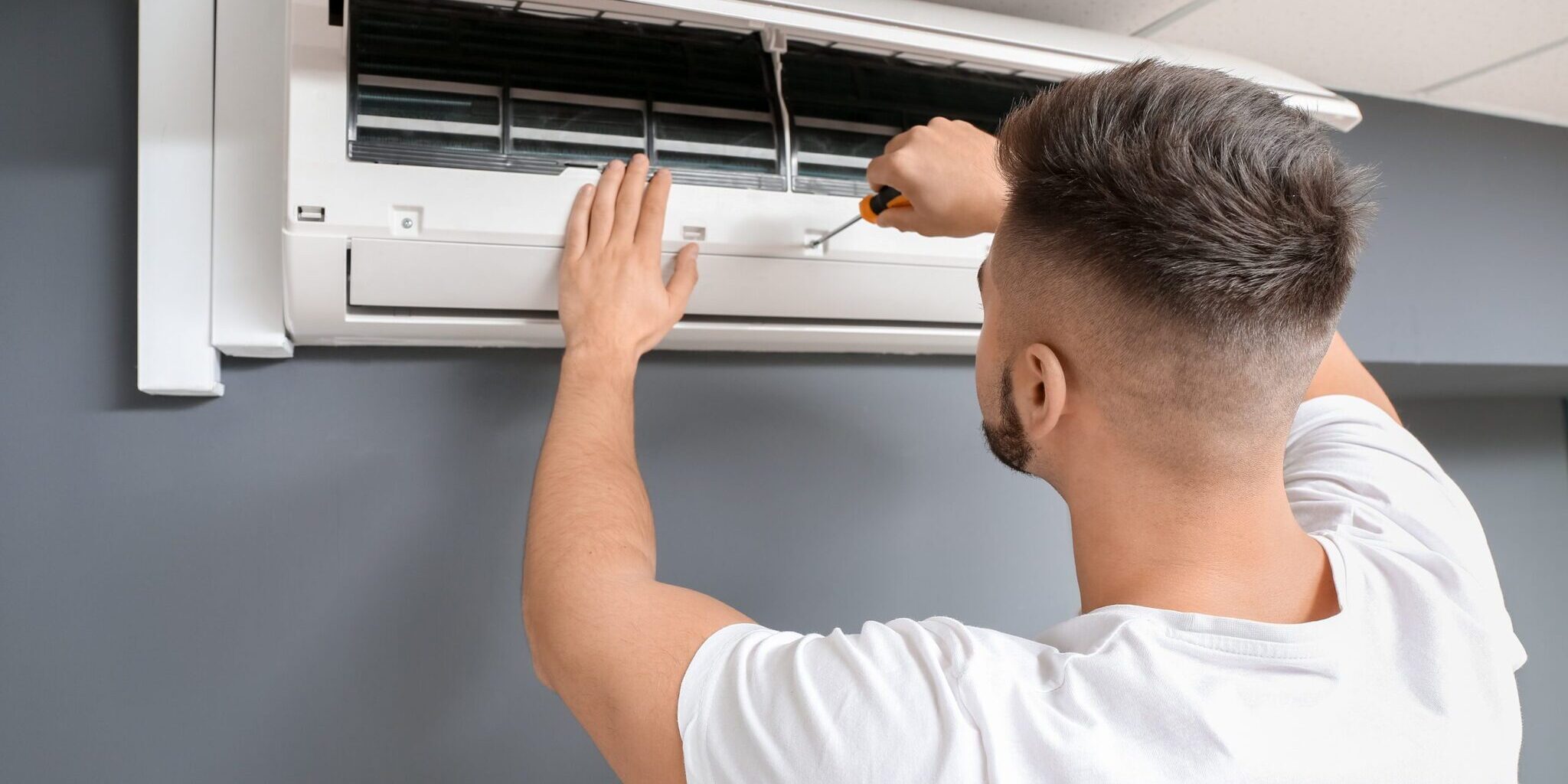 Male technician repairing air conditioner indoors
