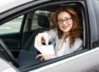 Vrouw toont met glimlach haar rijbewijs vanuit een geparkeerde auto, symbool voor behalen rijbewijs B