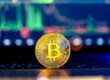 Een Bitcoin munt die staat voor een laptop met de koers op de achtergrond.