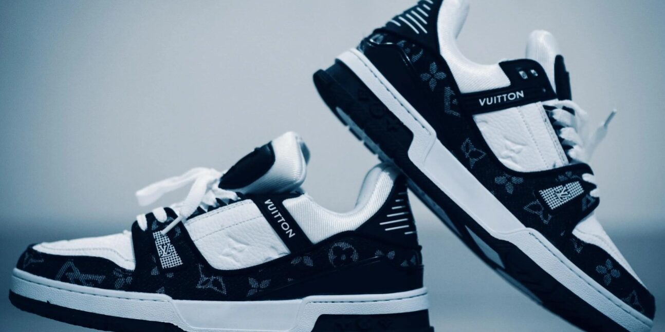 Zwart-witte Louis Vuitton sneakers met monogramdetails tegen een blauwe achtergrond