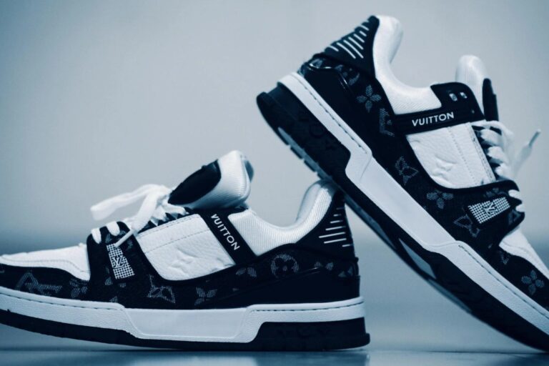 Zwart-witte Louis Vuitton sneakers met monogramdetails tegen een blauwe achtergrond