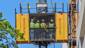 Bouwlift met werknemers op een bouwplaats voor materiaaltransport op hoogte