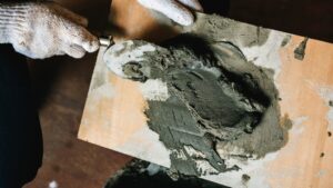 Cementmortel op troffel tijdens werkzaamheden die betonvloer en cementvloer verschil illustreren