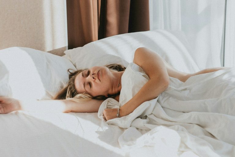 verschil-verzwaringsdeken-en-slaaptunnel Vrouw slaapt ontspannen onder een wit dekbed: het verschil tussen een verzwaringsdeken en een slaaptunnel